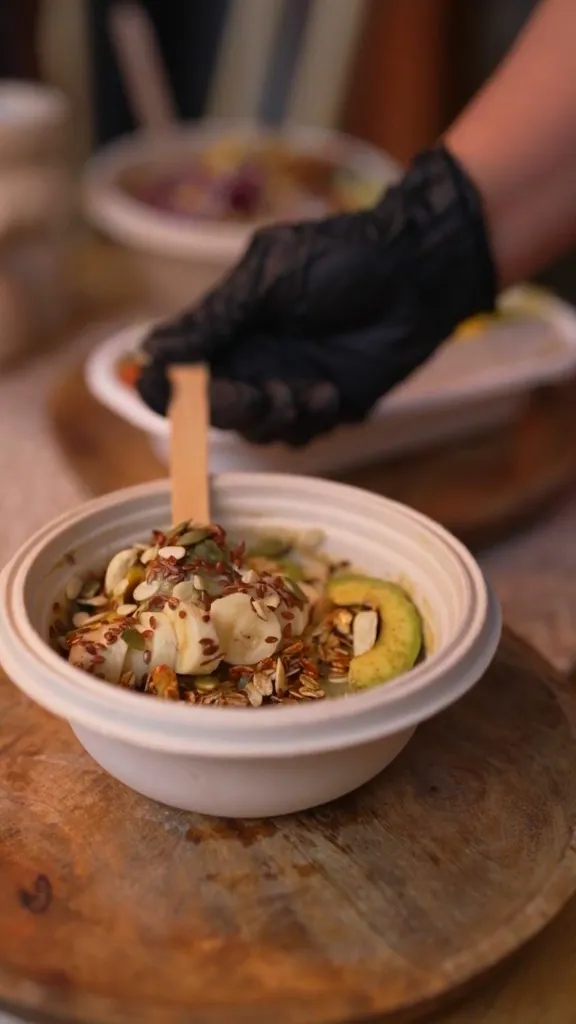Gloved chef plating a fresh smoothie bowl by hand at Clean & Green